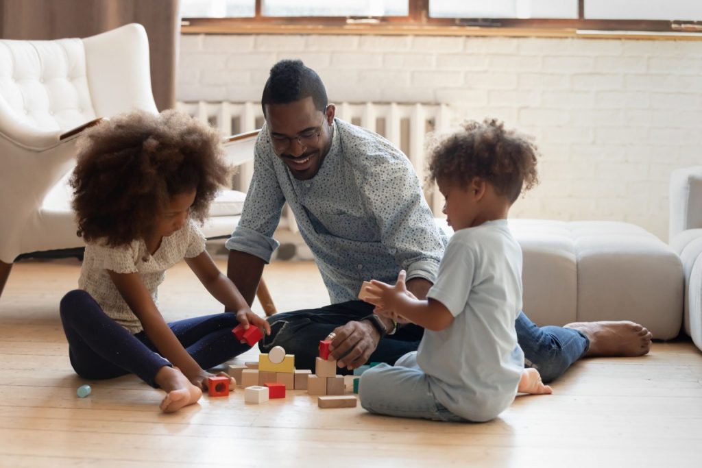 An image of a Father plaiting with his  Children