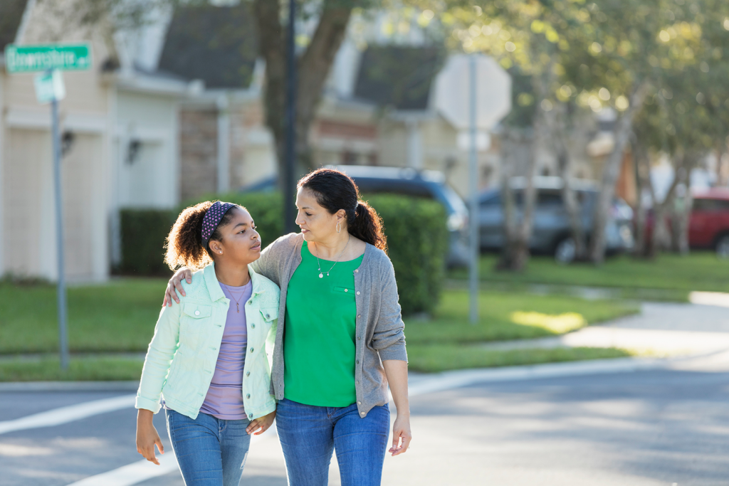 Woman and teenage girl walking in residential neighborhood