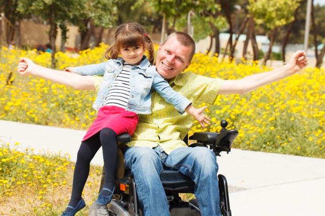 Father in wheelchair with daughter in his lap