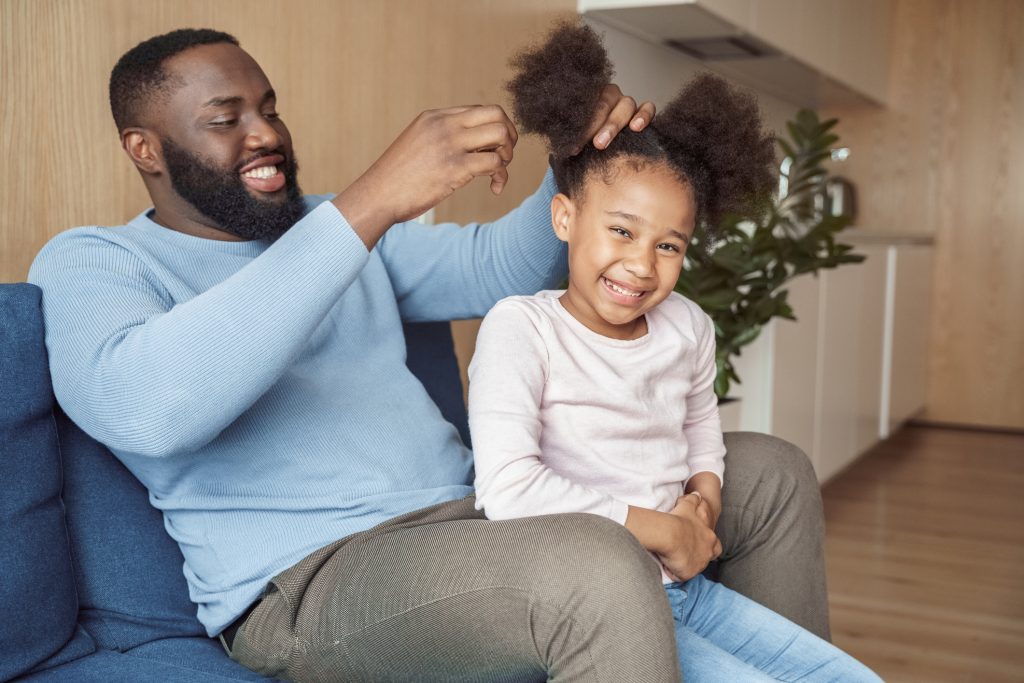 African American father combing daughter's hair