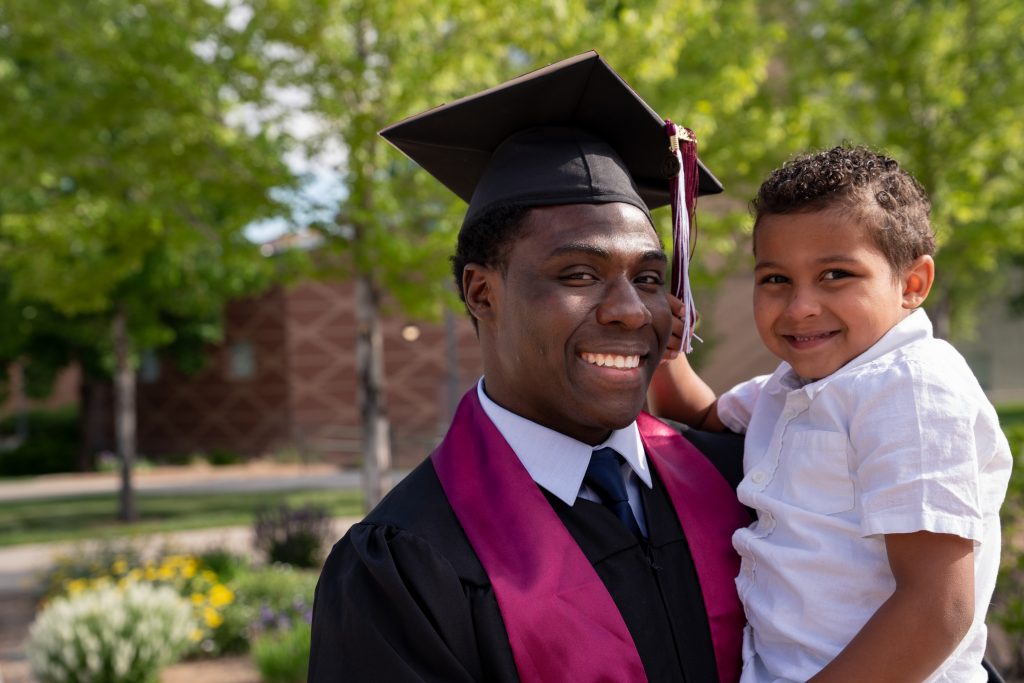 Father in graduation cap and gown holding a child