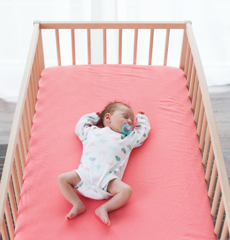 An image of a baby sleeping safely in a crib.