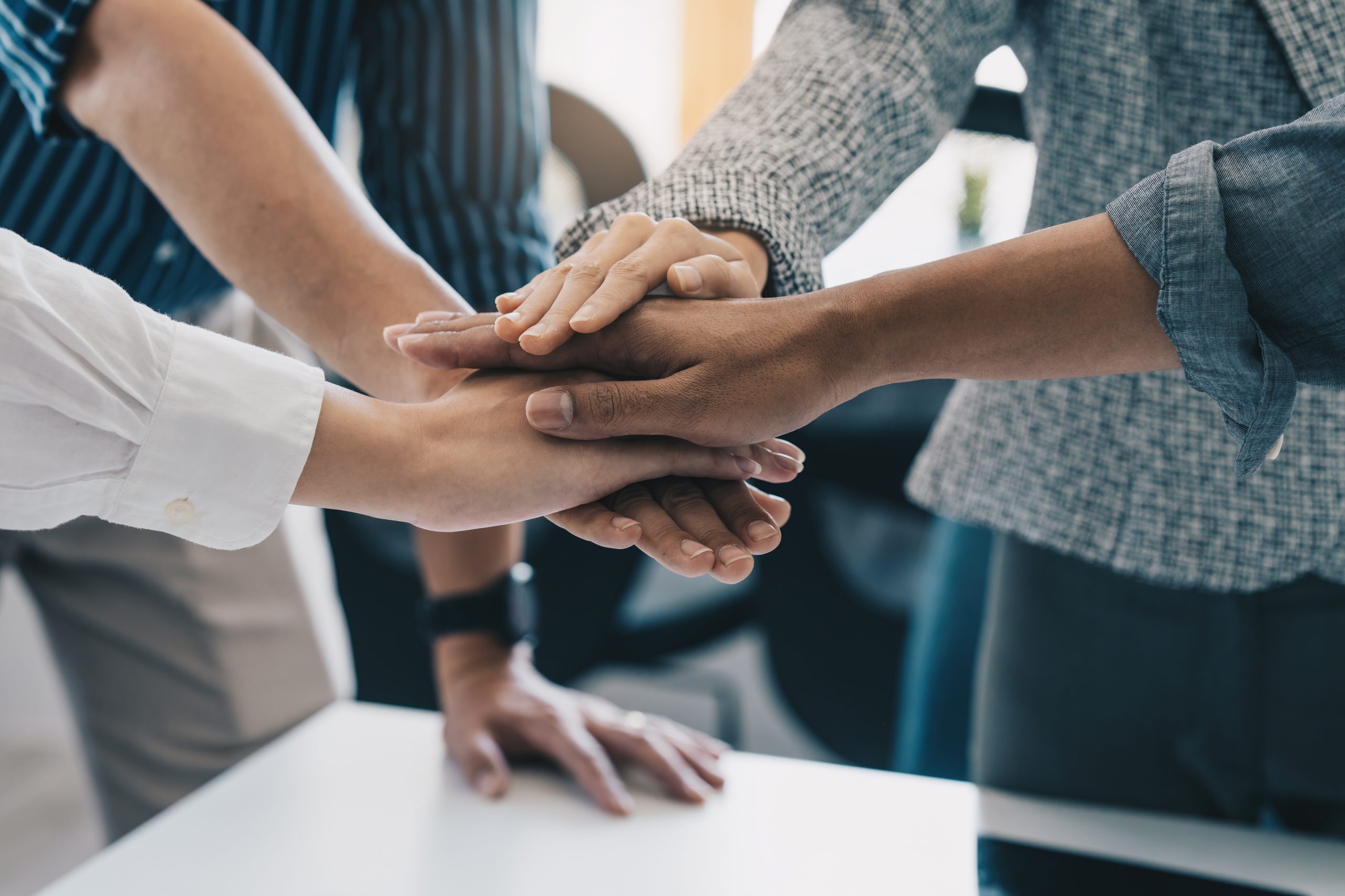 Group of business people putting their hands working together on wooden background in office.